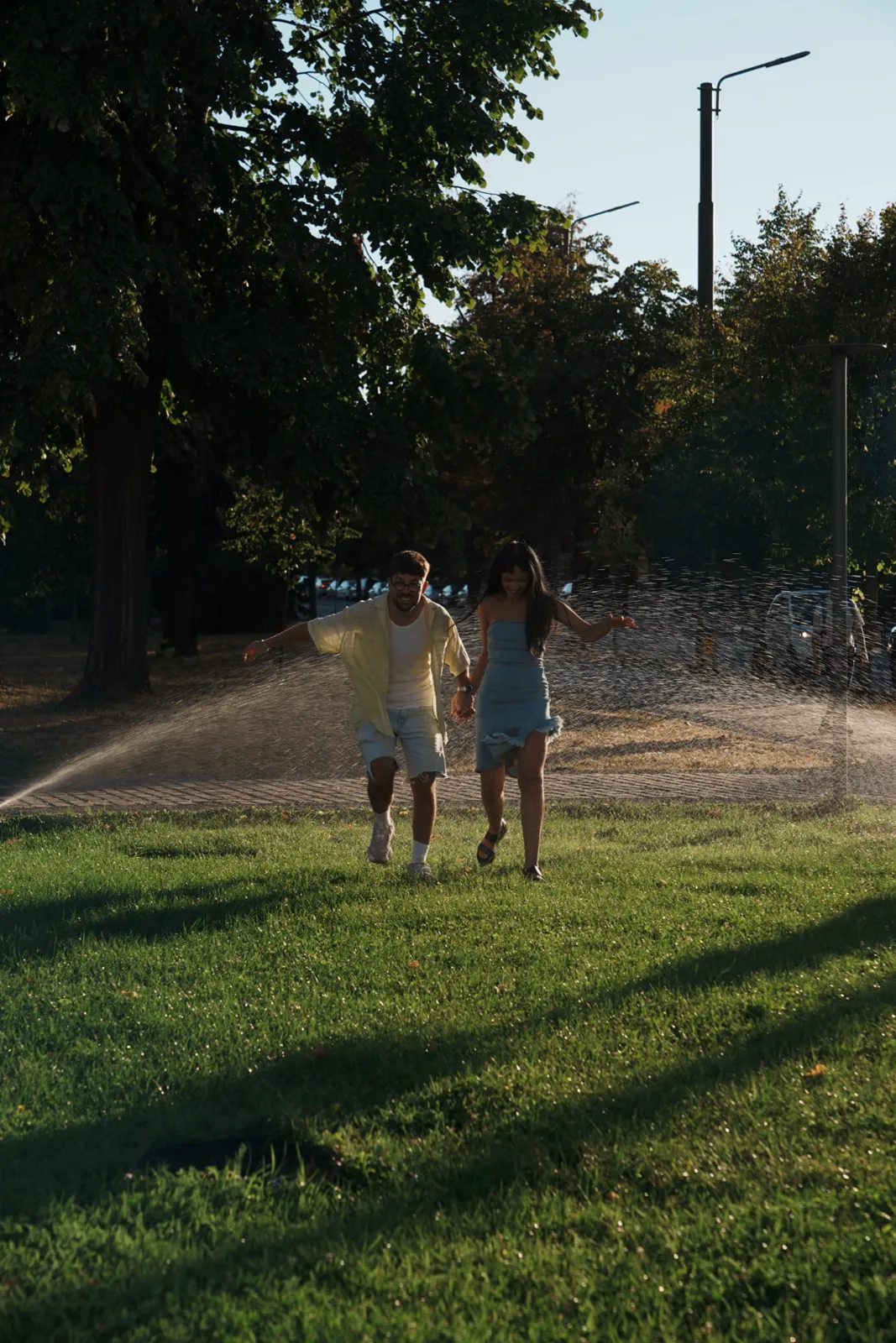 Couple running through sprinklers in a park in Timișoara