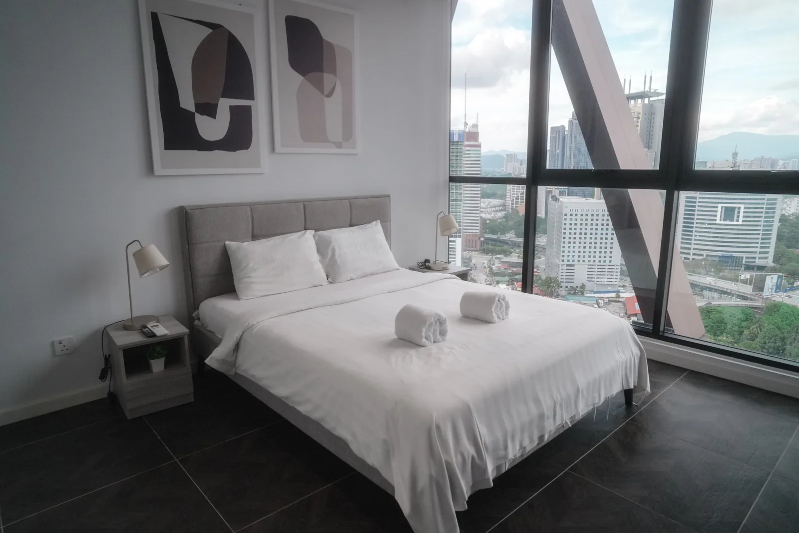 Cameră de hotel luminoasă cu fereastră panoramică spre oraș